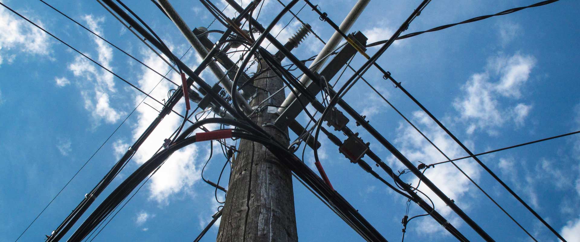 A brown utility pole with electrical wires.